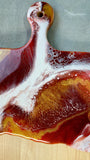 Our wood and resin serving boards offer an easy, unique entertaining solution that is ready to impress from big crowds to intimate gatherings for years to come setting the perfect stage for entertaining or gourmet gifts.  Beautiful swirl of reds, from very light to deep maroon, swirled with white accent resin. The waves have a hint of sparkles within it along with swirls, bubbles and more textures to enjoy as a work of art and also your guests will be amazed at the beauty of your serving ware.