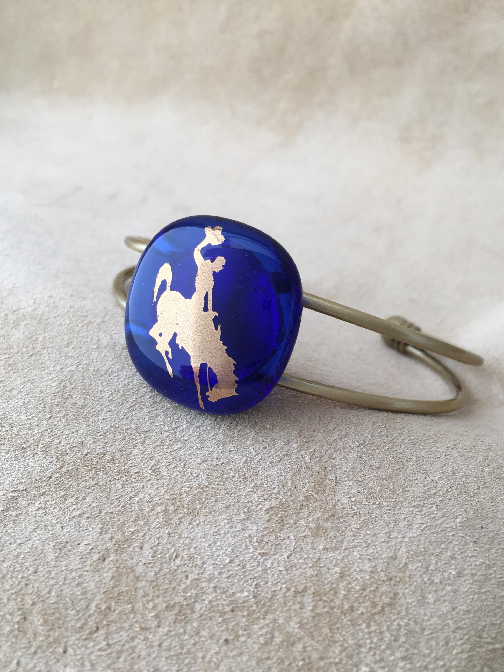 Cowgirl Blues Bucking Bronco Bracelet Leslie Irving, Artist Cowgirl Blues fused glass adjustable bracelet  Blue and Gold fused glass  22K Gold foil Bucking Horse and cowboy on Blue Fused Glass   Brass bracelet  Please note, the jewelry is   custom designed by the Artist , with a slight variation between each piece