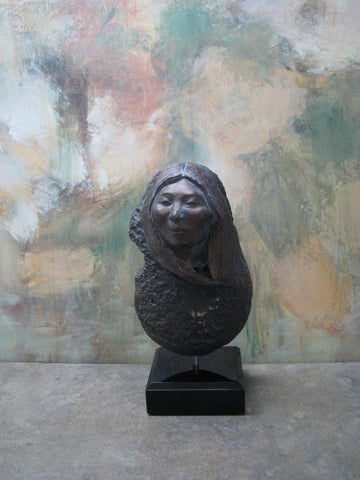 bronze face of a native american woman. textured stone as the body. attaches to the pin in the wooden base.