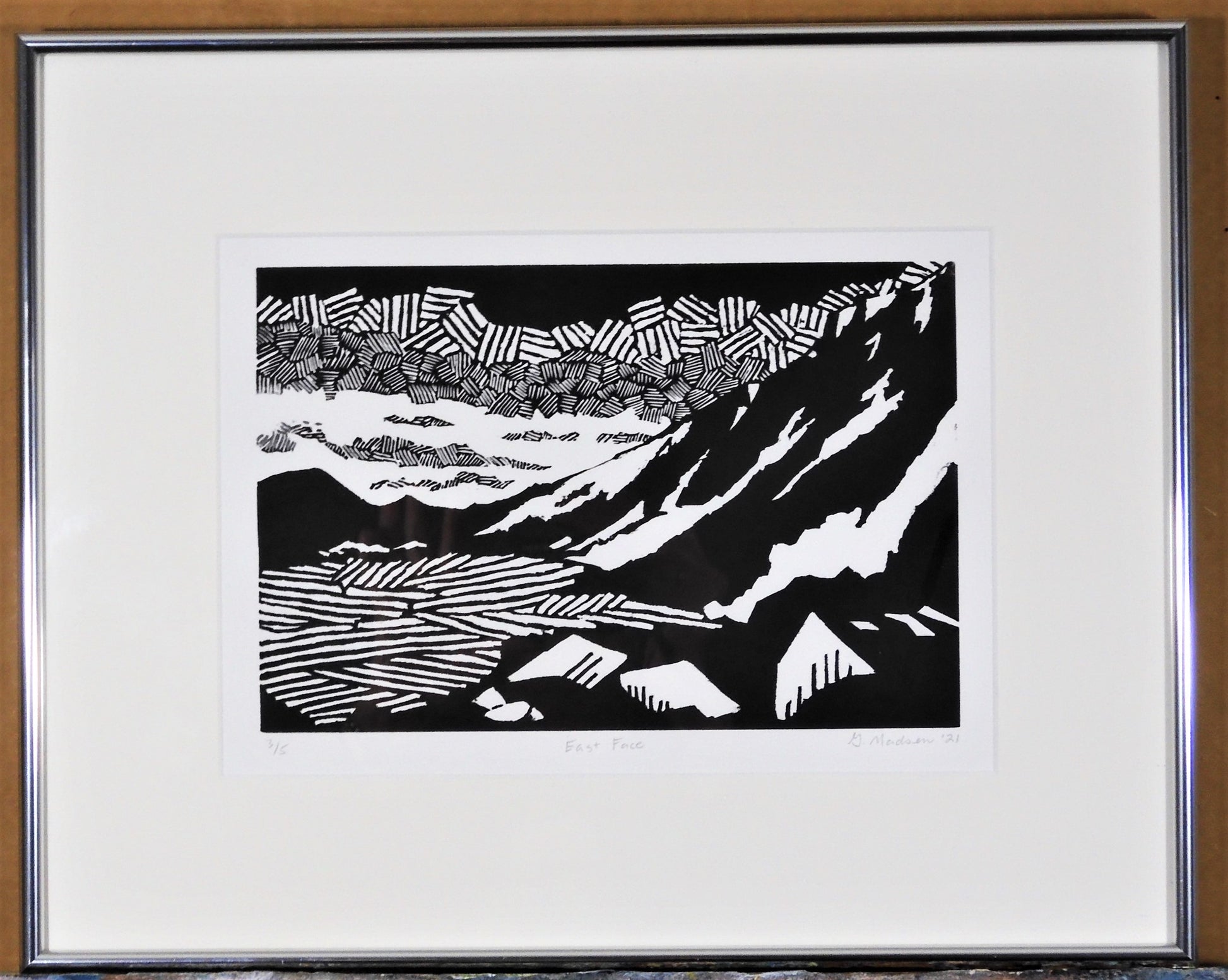 "East Face" Framed Relief Print Artist: Ginnie Madsen  Framed  White Mat  Narrow silver frame  Black and white image of the Snowy range mountains est of Laramie Wyoming  6" wide x 9" long x 1" deep print only  12" wide  x 15" long x 1" deep framed only  Relief print  Please note, each relief is custom designed by the Artist , with a slight variation between each relief print