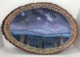 Gold Dust on Wood Slice Artist: Nancy Marlatt Painting of stars / mountains in and around Laramie WY on wood slabs with bark  Picture area is 13" wide x 11.25" Long x .75 thick  The picture is mix media on a wooden slice with bark  Picture would be great in a den, office or over a fire place  Please note, each miniature art piece is hand created by the Artist , with a slight variation between each piece