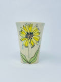 Hand thrown porcelain tall straight-sided tumbler  Yellow Sunflower motif is hand painted on the side of the tumbler  A blue wash gives added color to the porcelain  Glazed porcelain allows for everyday use  4" long x 4" wide x 5.5" high  It is suggested to hand wash the tumbler