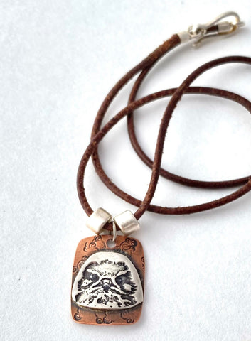 prairie falcon face on sterling silver. pendant soldered to copper back. on leather cord with sterling silver hook and eye clasp