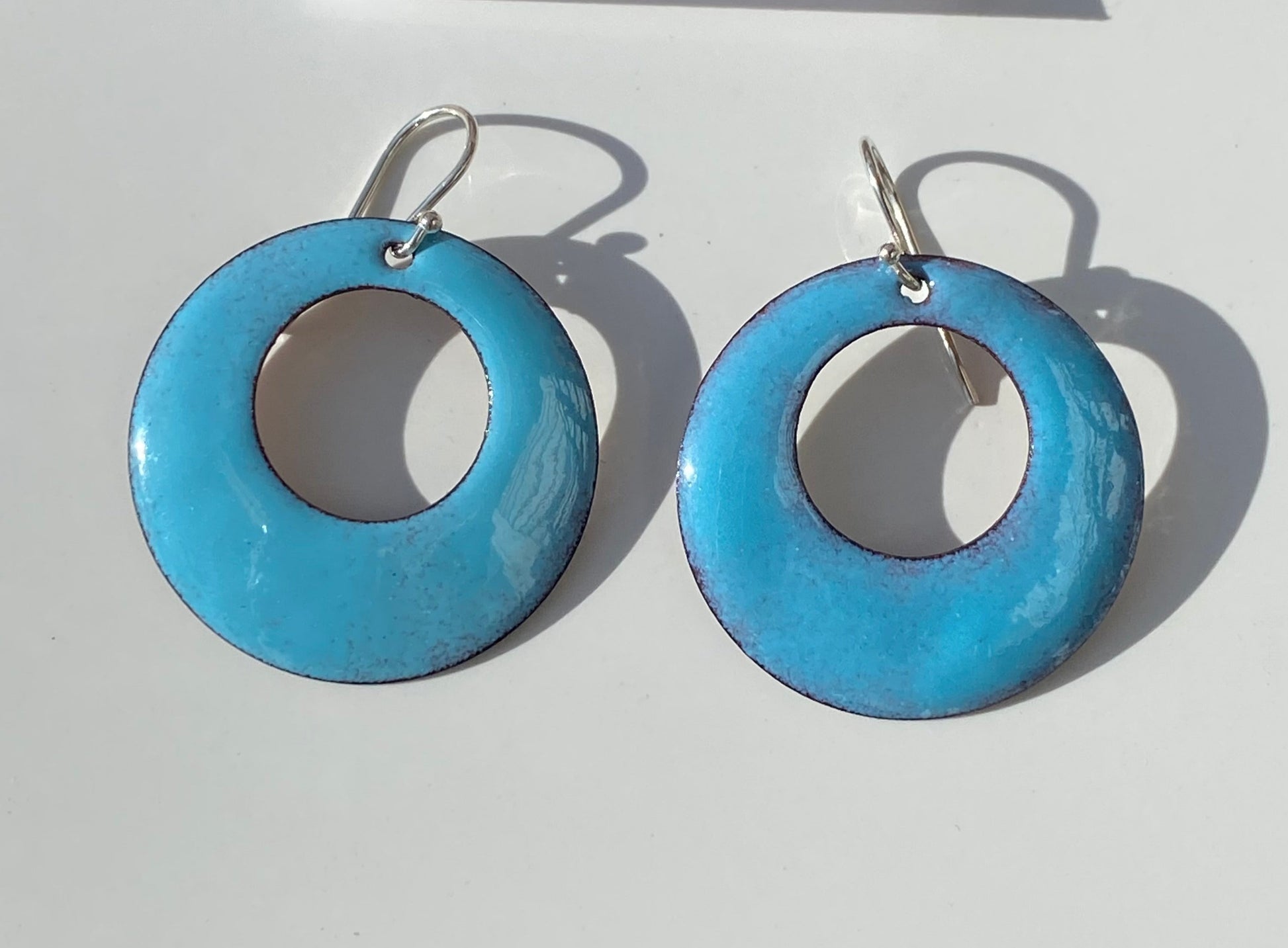 Pastel Blue Enamel Hoop Earrings Jewelry Artist: Kristie Brown Solid Pastel Blue enamel hoop  Hoop shape enamel earrings  1 1/2" across  Sterling Silver ear wires