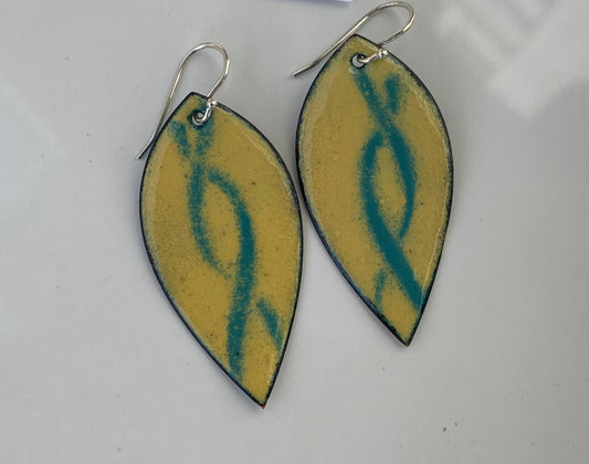 Teal Ribbon Enamel Earrings Jewelry Artist: Kristie Brown Teal ribbon design on an Ivory background  Leaf shape enamel earrings  2" long x 1" wide  Sterling Silver ear wires