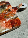 Artisan Walnut Cheese Board / Handle Artist: Marcy Knotwell  Copper penny, white, gray and liquid copper lacing resin design  You will not be disappointed with the quality of this product! Our handcrafted wood grained-edge charcuterie cheese boards are the answer to stylish, multi-functional, sustainable serve-ware.  When not in use, this charcuterie cheese board makes a beautiful addition to your countertop or gallery wall.