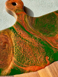 Artisan Crafted Cheese Board / Handle Artist: Marcy Knotwell  Copper penny, green and copper penny resin design  You will not be disappointed with the quality of this product! Our handcrafted wood grained-edge charcuterie cheese boards are the answer to stylish, multi-functional, sustainable serve-ware.  When not in use, this charcuterie cheese board makes a beautiful addition to your countertop or gallery wall.