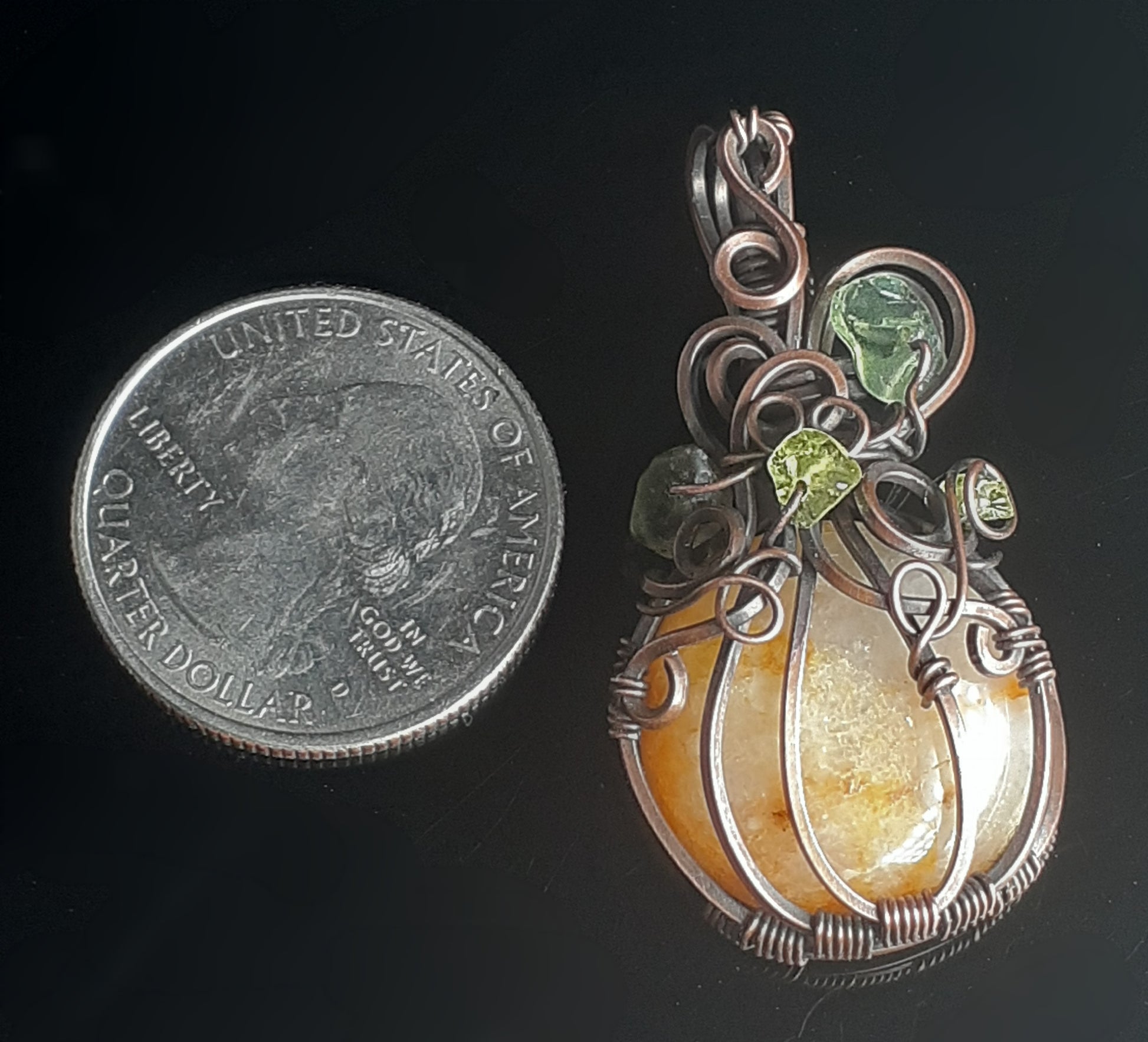Apricot Quartz Pumpkin Pendent  Artist: Lindsey Griffin   Apricot Quartz with Peridot wrapped in oxidized copper   Brown leather cord for wearing as a necklace   1 8/16" Long x 15/16" Wide x 1/4" Deep