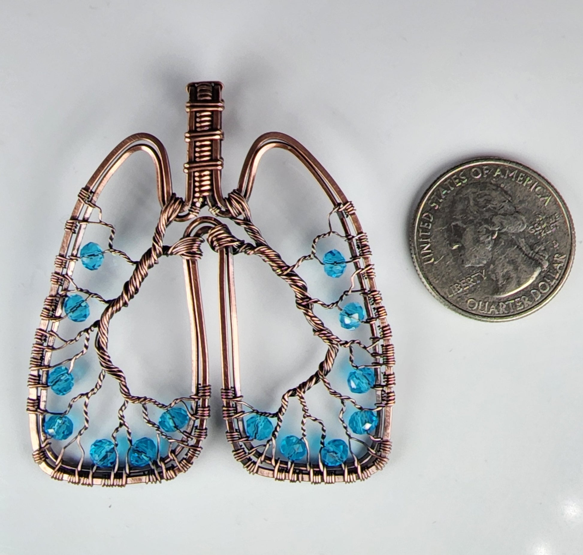 Anatomical Lungs Pendant with Pale Blue Beads Wire Wrapping Artist: Lindsey Griffin  Oxidized Polished Copper wire  Pale Blue High Quality glass beads  Perfect and unique gift for a specialist, doctor, nurse, therapist and more, who deals with lungs and pulmonary  Widest horizontal measurement - 2.25"  Longest vertical measurement: 2 5/8"