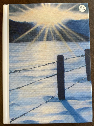 Artwork covering front and back of Hardcover Journal features a barbwire fence line in the snow with sunshine and mountains