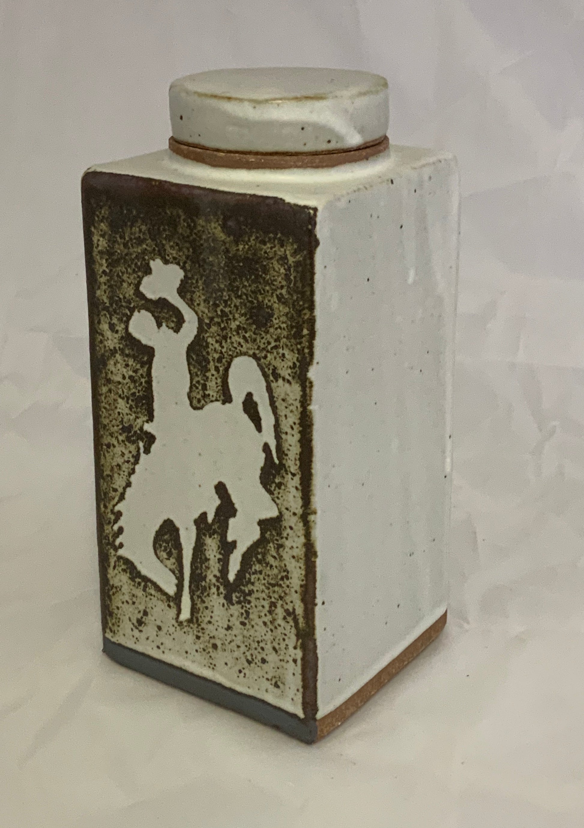 Medium Ceramic Rectangle Stoneware Bucking Horse Jar Muffy Moore Ceramic Potter Rectangle Bucking Horse Jar 2.5" L x  2.5" w x 6" H  Stoneware  Very Decorative Piece White with Bucking Horse, Steamboat, the UWYO logo. in Brown/White