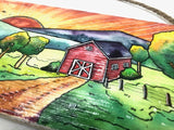 Sealed with an acrylic Gloss finish  12" long x 5 1/4" high x 1/4" wide  Brilliant Sunset behind the hills  Scene of a red barn with trees and fence around it and a nearby pond
