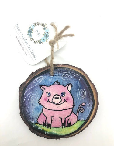 " Piggie" Hand Painted Wooden Ornament Artist: Nancy Marlatt  Original watercolor painting on a small slice of wood  Hand painted natural wood slice with a jute string attached  May be displayed as miniature artwork or as a holiday tree ornament  Painted with professional grade watercolors, gouache, and acrylic ink pens  Top is sealed with a Mod Podge finish  Surface was treated with a transparent watercolor ground  Actual size and weight varies per piece  Hand signed by the artist  3" x 3" x .25"