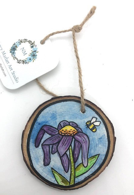 " Bumble Bee " Hand Painted Wooden Ornament Artist: Nancy Marlatt  Hand painted natural wood slice with a jute string attached  Original watercolor painting  Actual size and weight varies per piece  Hand signed by the artist  Whimsical Purple Flower ( Could be a daisy or cosmos)  Bumble Bee headed for nectar  Blue and white sky background  2.75" x 2.75"x  .25"