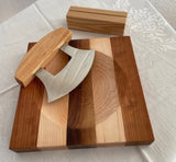 ULU Knife with Stand and Cutting Board, perfect for your dining preparation!. Created from various hardwoods, the center of the board is routered out for cutting ease. A protective stand for the knife is included.