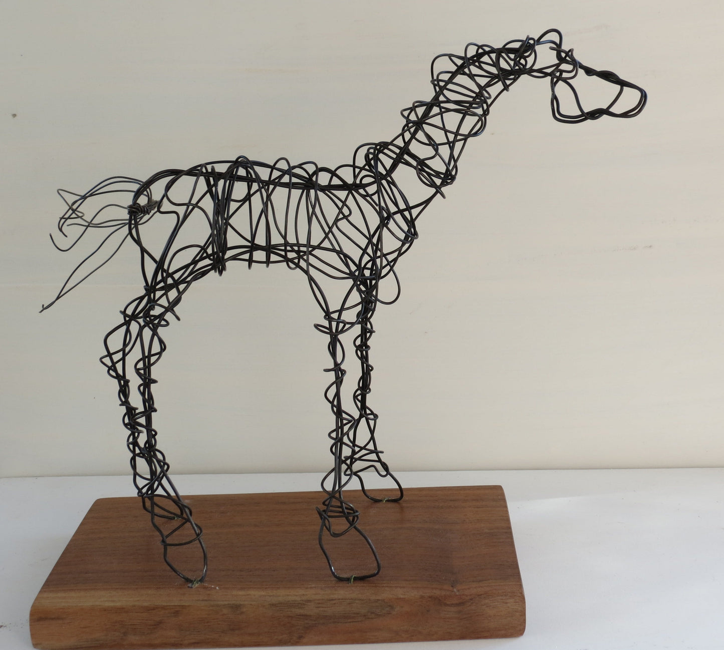 Hay baling wire bend and sculpted into a wire horse statue. On a walnut base