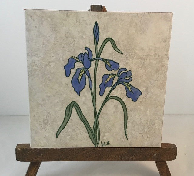 Iris trivet Artist: Elizabeth Rulli A recycled trivet from Habitat for Humanity  Restore with a Indian Paintbrush hand paint on trivet  Wood bottom with felt pads on bottom coroners  Hand painted and fired to 1375 degrees and will clean with scouring power if a pan leaves a mark  Wild Iris painted on each trivet