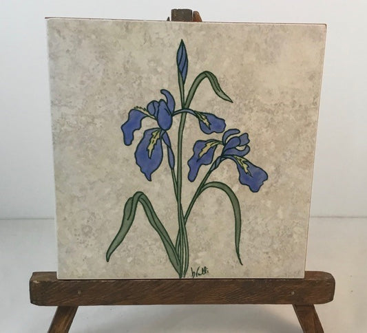 Iris trivet Artist: Elizabeth Rulli A recycled trivet from Habitat for Humanity  Restore with a Indian Paintbrush hand paint on trivet  Wood bottom with felt pads on bottom coroners  Hand painted and fired to 1375 degrees and will clean with scouring power if a pan leaves a mark  Wild Iris painted on each trivet