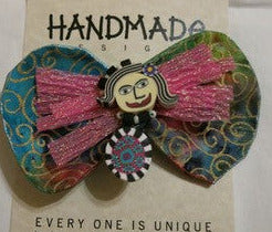 "Fabric Bow Tie Girl" Pin Artist: Glenda Haley Colorful bow tie girl with a face and body and a bow tie behind her with a pin attachment  4" long x 2" wide x 1/8" deep   Beautiful hand made bow ties great with blue jean outfit or with a blazer for a night out   Each piece is hand done by artist, so there will be slight variation
