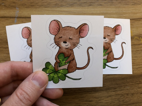 " Lucky Mouse " Sticker Artist:  Tara Pappas  Whimsical sticker of a mouse holding a four leaf clover sticker  Sticker has a white background  1 1/2" Long x 2 1/4" Wide x 1/16" Deep  Would look great on a water bottle or laptop and other things