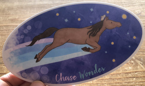 " Chase Wonder " Horse And Rabbit Sticker Artist:  Tara Pappas  Whimsical sticker of a horse leaping with a rabbit riding on horse's head  Night sky background  Chase Wonder written at the bottom  Oval sticker  Sticker has a white background  6" Long x 3 3/4" Wide  Would look great on a water bottle or laptop 