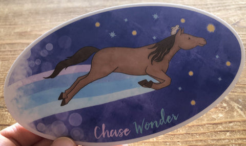 " Chase Wonder " Horse And Rabbit Sticker Artist:  Tara Pappas  Whimsical sticker of a horse leaping with a rabbit riding on horse's head  Night sky background  Chase Wonder written at the bottom  Oval sticker  Sticker has a white background  6" Long x 3 3/4" Wide  Would look great on a water bottle or laptop 
