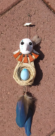Mixed media clay head with glass bead eyes  Wooden and metal necklace with beads  Handmade Rafia nest with painted clay egg inside  All attached to a wooden bakc  Natural feathers for accents  3" long x 3" wide x 15" high
