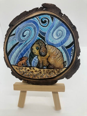 Holland lop rabbit and baby rabbit meet an become friends  3.5" to 4" Hand Painted round wood slice magnet  Painted with an original mixed water media  Surface is sealed with a magnet attached to the back of the wood slice  Ready to hang on a magnetic surface or displayed on an easel (not included)  Title of the artwork piece written on the back